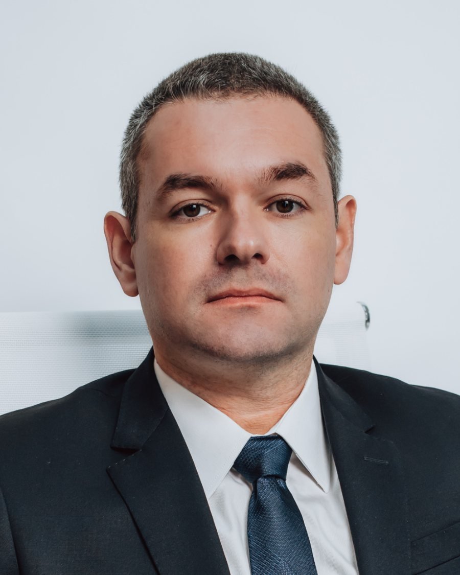 Retrato de Diego Anfiloquio, advogado, de terno escuro e gravata azul sobre fundo claro